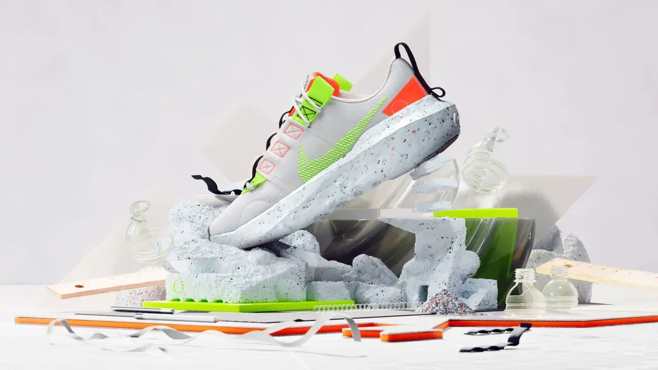Nike Move to Zero: Ein weißer Schuh mit neongrünen Akzenten, der auf einer skulpturalen Basis aus recyceltem Material steht.