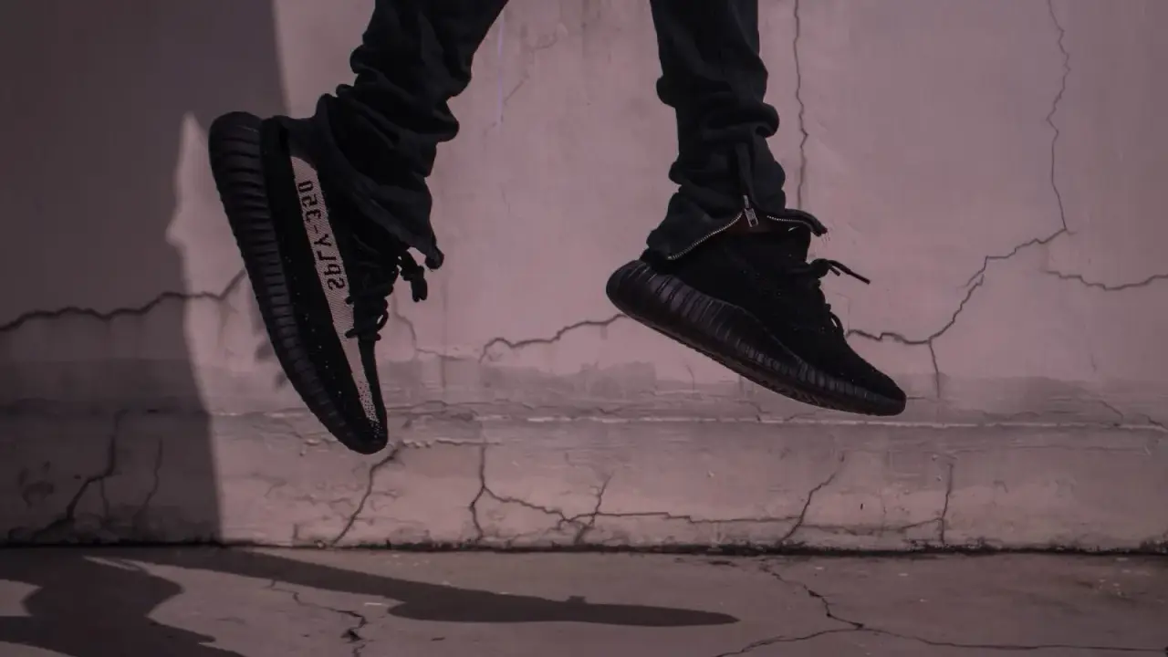Schwarze Yeezy binden, die in der Luft schweben, mit einem Streifen auf der Seite.