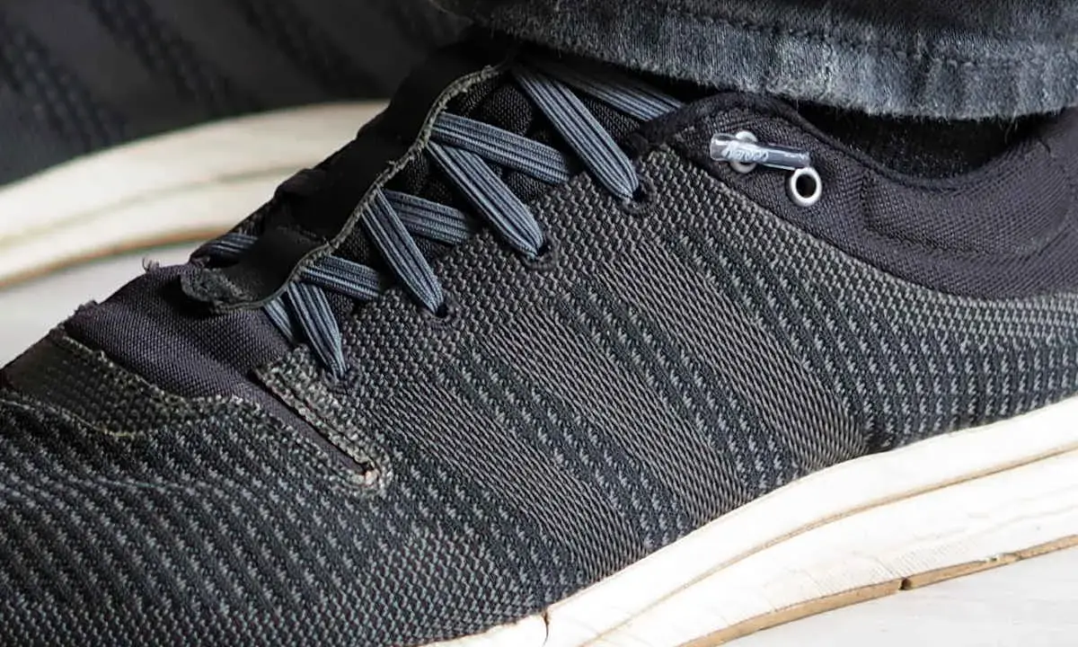 Schuhe binden ohne schleife: Schnürsenkel sind durch Ösen geführt und mit einem Stopper fixiert, was schnelles Anziehen ermöglicht.