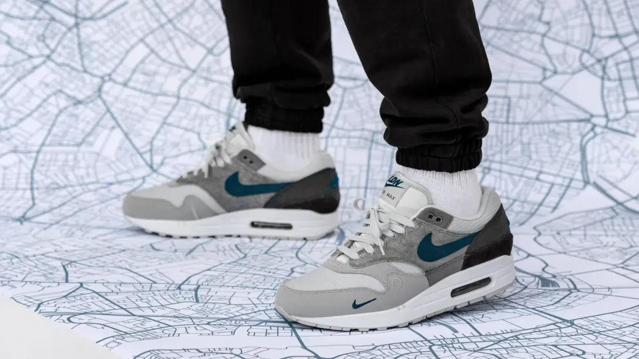 Graue Air Max 1 Sneaker mit türkisfarbenem Swoosh auf einer Stadtkarte. Perfekt für den nächsten Air Max 1 Release!