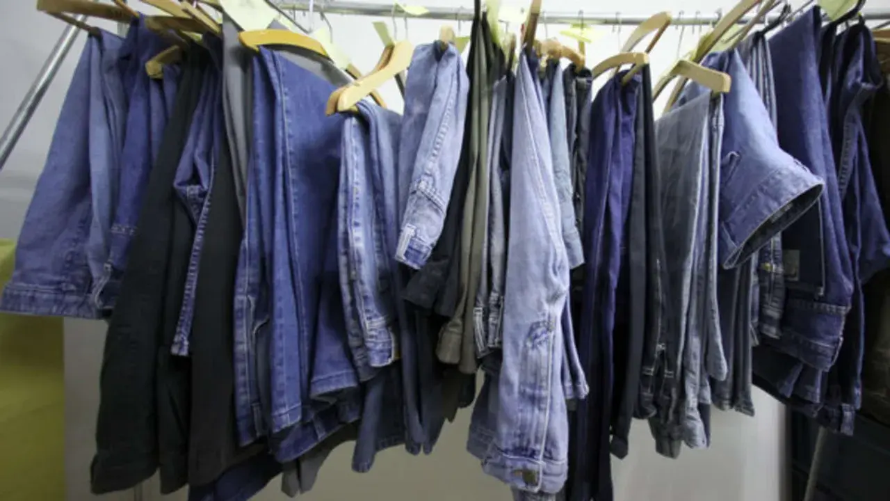 Eine Reihe von Jeans hängt an Kleiderbügeln. Manche sind hellblau, andere dunkelblau. Sie sind bereit, um sie bei 60 Grad zu waschen.
