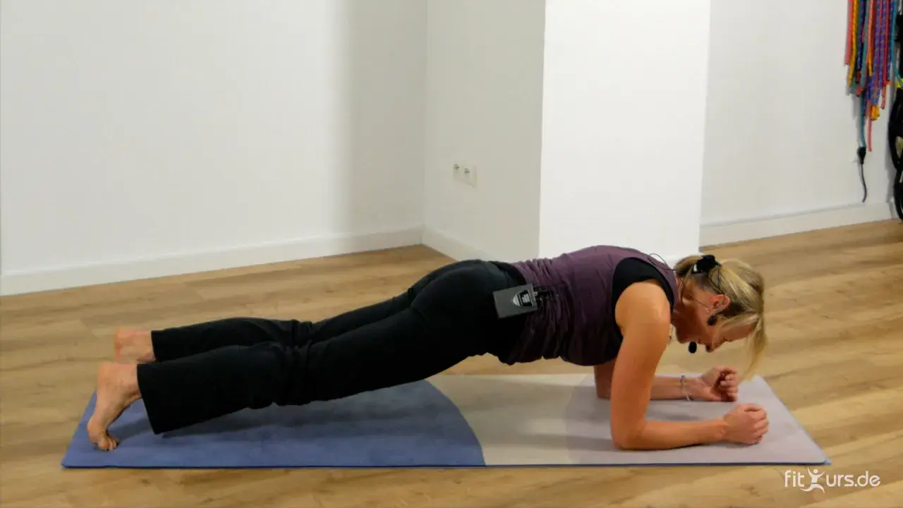 Frau in Unterarmstütz-Position auf einer Matte.