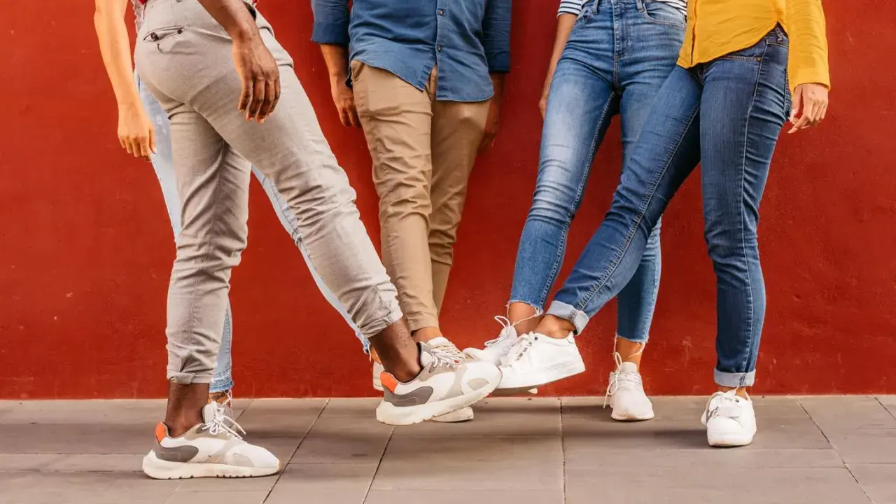 Vier Personen mit stylischen Sneakern stoßen ihre Füße aneinander. Perfekt für einen Sneaker-Blog!