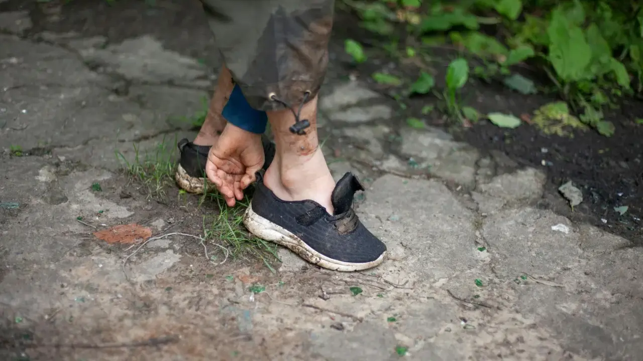 Schmutzige Turnschuhe auf dem Boden, die Person versucht, sie zu trocknen.