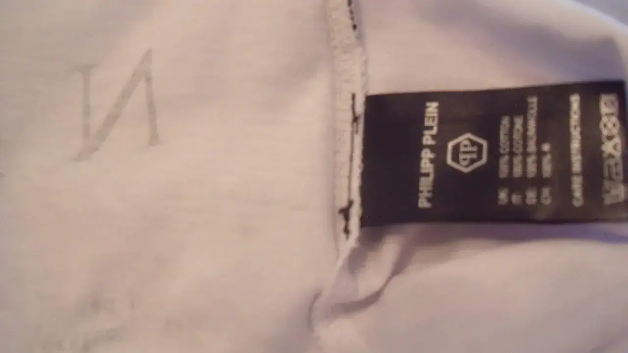 Etikett mit "Philipp Plein" und dem PP-Logo. Ein undeutliches "N" ist auf dem Stoff zu sehen. So erkennt man ein Philipp Plein Fake.