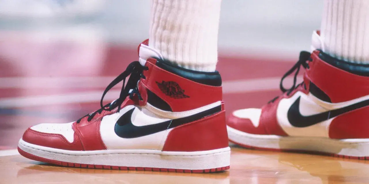 Die ersten Jordan Schuhe, rot-weiß-schwarz, auf einem Basketballfeld. Ein ikonischer Sneaker-Moment.