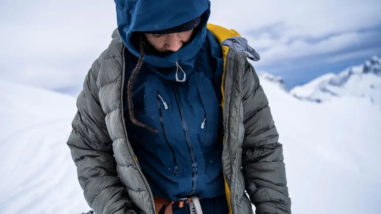Person in Daunenjacke im Schnee. Tipps zum daunenjacke waschen für optimale Wärme.
