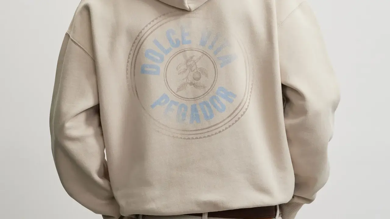 Rückseite eines beigen Hoodies mit rundem Aufdruck "Dolce Vita Pegador". Wo produziert Pegador?