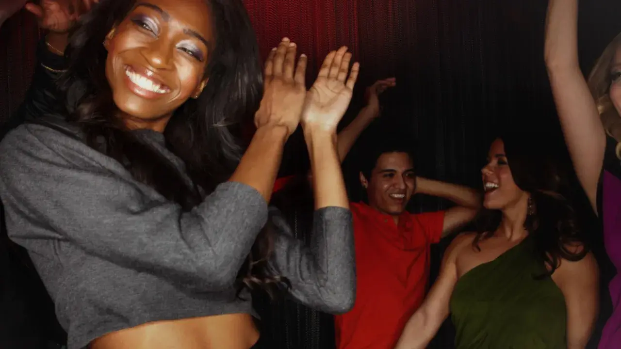 Glückliche Menschen tanzen im Club. Sie tragen modische Kleidung, die perfekt ist, wenn man im Club ist.