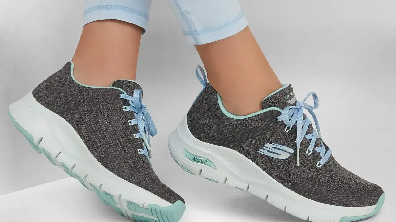 Graue Skechers-Sneaker mit hellblauen Schnürsenkeln und mintgrünen Akzenten. Die Sohlen zeigen die Skechers Sohlen Unterschiede, mit einer markanten ArchFit-Technologie.