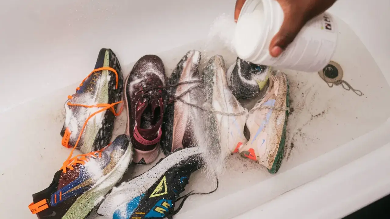 Mehrere Laufschuhe werden in einer Wanne mit einem Pulver bestreut, um sie zu reinigen und zu desinfizieren.