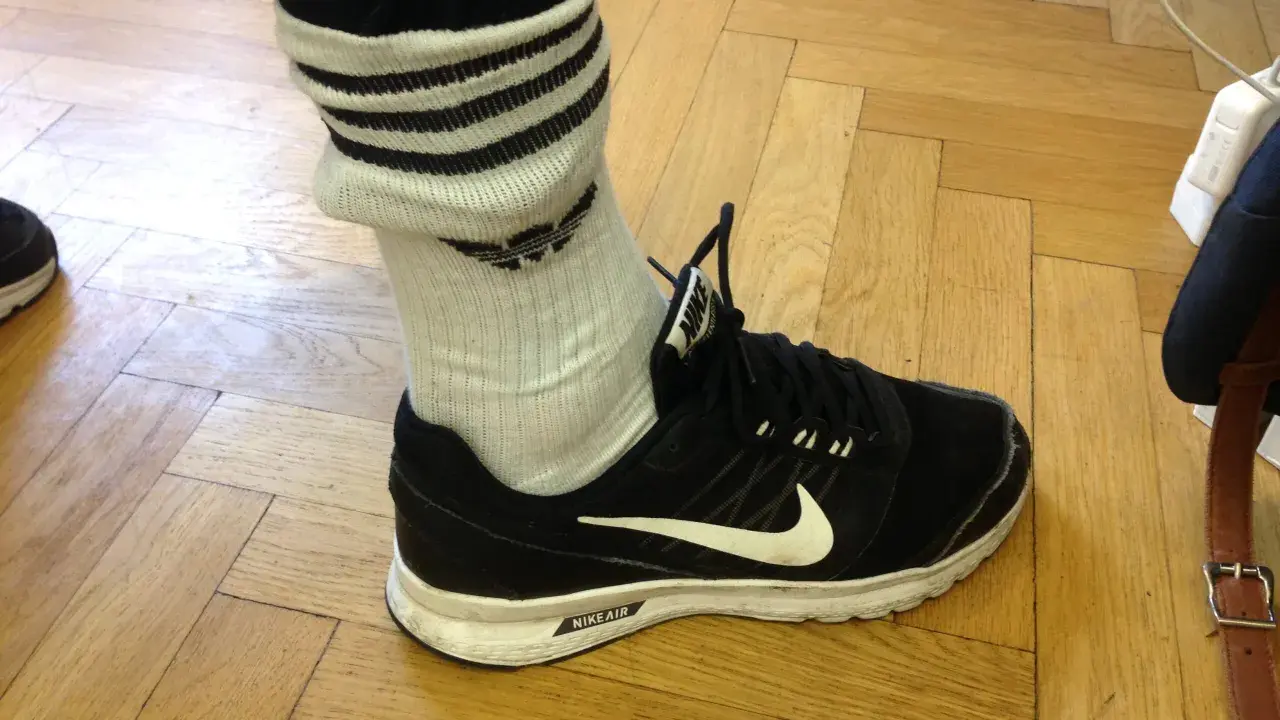 Schwarzer Nike-Schuh mit weißen Streifen an den Socken, die über den Knöchel reichen.