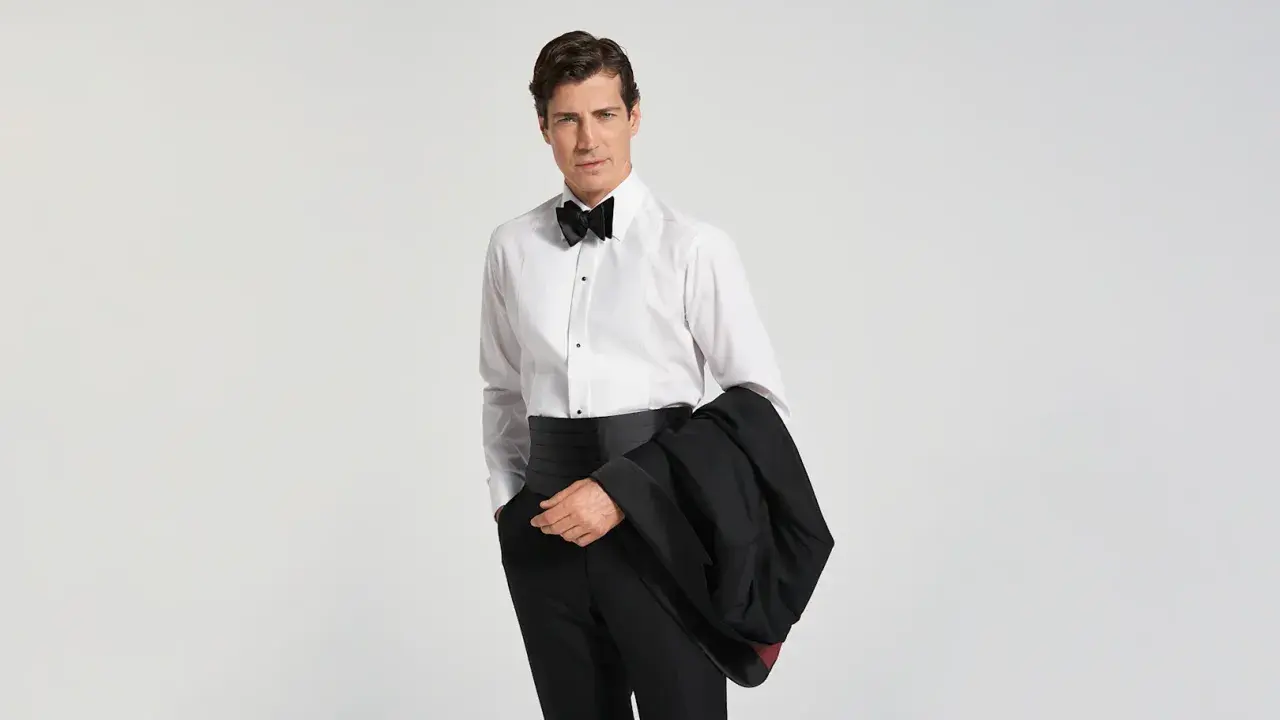 Mann im Smoking mit Fliege und Kummerbund, bereit für den black tie dresscode herren.