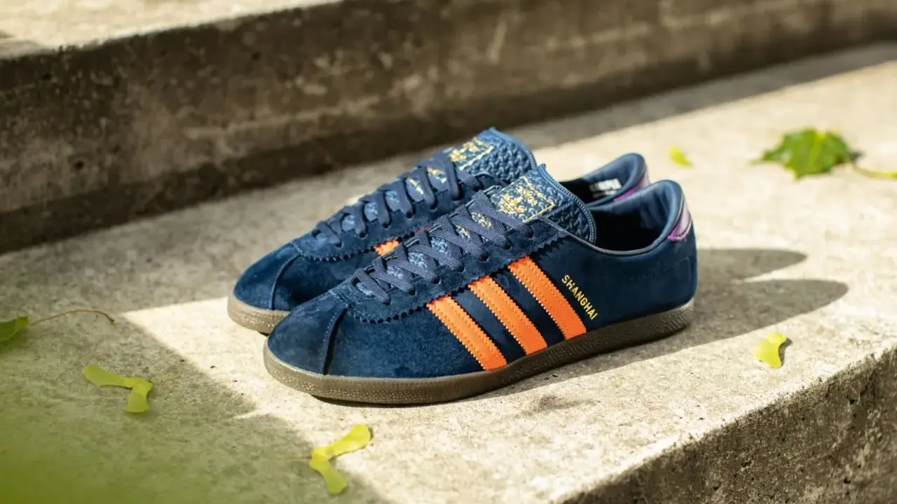 Adidas City Series: dunkelblaue Sneaker mit orangefarbenen Streifen und "Shanghai"-Schriftzug, perfekt für urbane Entdecker.