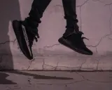 Schwarze Yeezy binden, die in der Luft schweben, mit einem Streifen auf der Seite.
