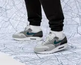 Graue Air Max 1 Sneaker mit türkisfarbenem Swoosh auf einer Stadtkarte. Perfekt für den nächsten Air Max 1 Release!