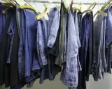 Eine Reihe von Jeans hängt an Kleiderbügeln. Manche sind hellblau, andere dunkelblau. Sie sind bereit, um sie bei 60 Grad zu waschen.