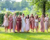 Brautjungfern in zarten Rosatönen, ein perfekter **dresscode hochzeit**, spazieren lachend über eine grüne Wiese.