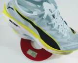 Leichter Laufschuh in Hellblau mit gelben und schwarzen Akzenten auf einer Waage. Das Gewicht der Schuhe beträgt 389 Gramm.
