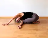Frau in Yoga Kindhaltung auf dem Boden, entspannt und mit geschlossenen Augen.