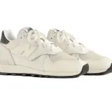 Cremefarbene Sneaker mit Teddy Santis Design, Mesh- und Lederdetails, weiße Schnürsenkel und schwarze Sohle.