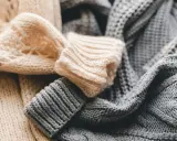 Weiche, gestrickte Pullover in Beige und Grau liegen übereinander. Bald ist Zeit für die **Wolle waschen**, damit sie wieder frisch duften.