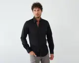 Mann in schwarzem Hemd mit farbigem Kragen und grauer Hose. Ein stilvoller Look, wie man ein schwarzes Hemd kombinieren kann.