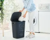 Eine Person legt weiße Wäsche in einen Wäschekorb, bereit, die Jacke zu waschen.