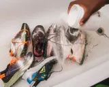 Mehrere Laufschuhe werden in einer Wanne mit einem Pulver bestreut, um sie zu reinigen und zu desinfizieren.