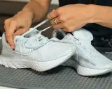 Hände ziehen Schnürsenkel durch hellblaue Mesh Schuhe. So einfach lassen sich die Lieblingssneaker reinigen.