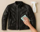 Schwarze Lederjacke reinigen mit einem Tuch und Sprühflasche. Pflegen Sie Ihre Lederjacke für lange Haltbarkeit.