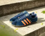 Adidas City Series: dunkelblaue Sneaker mit orangefarbenen Streifen und "Shanghai"-Schriftzug, perfekt für urbane Entdecker.