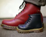 Zwei Dr. Martens Stiefel, ein roter und ein schwarzer, zeigen die Qualität des Dr. Martens Leder.