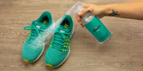 Grüne Nike-Laufschuhe werden mit einem Spray besprüht, um zu verhindern, dass die schuhe stinken. Was tun?