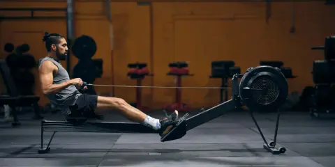 Mann auf Rudergerät, trainiert intensiv. Rudern ist ideal für den Kalorienverbrauch und ein Ganzkörpertraining.