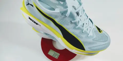 Leichter Laufschuh in Hellblau mit gelben und schwarzen Akzenten auf einer Waage. Das Gewicht der Schuhe beträgt 389 Gramm.