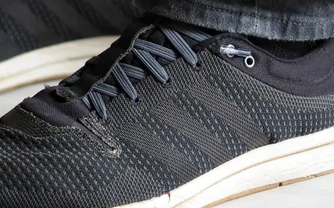 Schuhe binden ohne schleife: Schnürsenkel sind durch Ösen geführt und mit einem Stopper fixiert, was schnelles Anziehen ermöglicht.