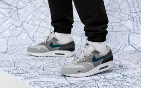 Graue Air Max 1 Sneaker mit türkisfarbenem Swoosh auf einer Stadtkarte. Perfekt für den nächsten Air Max 1 Release!