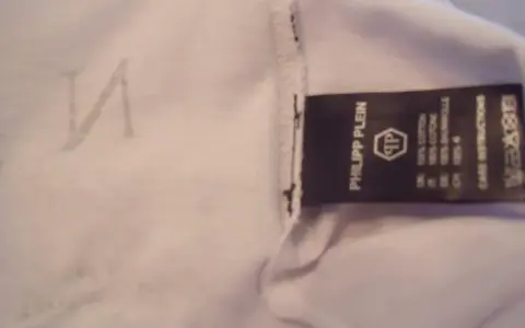 Etikett mit "Philipp Plein" und dem PP-Logo. Ein undeutliches "N" ist auf dem Stoff zu sehen. So erkennt man ein Philipp Plein Fake.