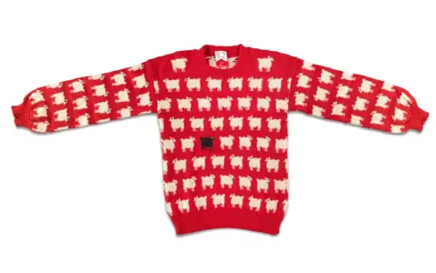 Roter Pullover mit weißem Schafmuster und einer schwarzen Schaf-Applikation in der Mitte. Ein echter Hingucker, vielleicht der teuerste Pullover der Welt?