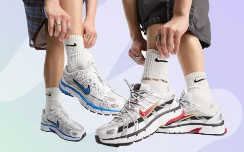 Zwei Paare Nike P-6000 Sneaker in Weiß mit blauen und roten Akzenten. Die Füße tragen weiße Socken mit Nike-Logo und auffälligen Schmuck.