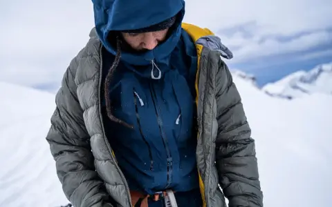 Person in Daunenjacke im Schnee. Tipps zum daunenjacke waschen für optimale Wärme.