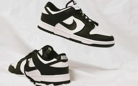 Zwei schwarz-weiße Nike Dunk Low Sneaker schweben auf weißem Stoff. Sie fallen größtenteils größengerecht aus.