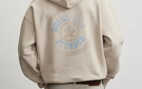 Rückseite eines beigen Hoodies mit rundem Aufdruck "Dolce Vita Pegador". Wo produziert Pegador?