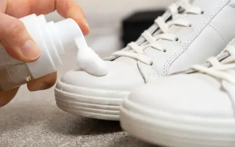Schaum wird auf weiße Sneaker aufgetragen, um sie sauber zu machen.