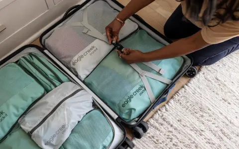 Frau packt ihren Koffer mit Packwürfeln. So packe ich meinen Koffer für die Reise, ordentlich und platzsparend.