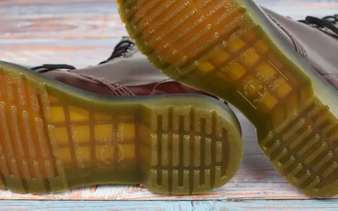 Die charakteristische, gelbe Naht und das Profil der **Dr. Martens Sohle original** sind auf dem Holzuntergrund zu sehen.