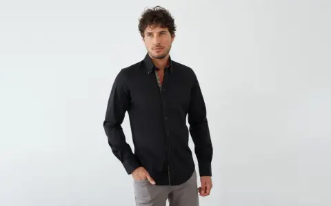 Mann in schwarzem Hemd mit farbigem Kragen und grauer Hose. Ein stilvoller Look, wie man ein schwarzes Hemd kombinieren kann.
