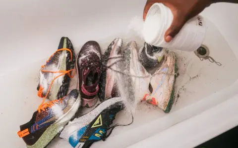 Mehrere Laufschuhe werden in einer Wanne mit einem Pulver bestreut, um sie zu reinigen und zu desinfizieren.