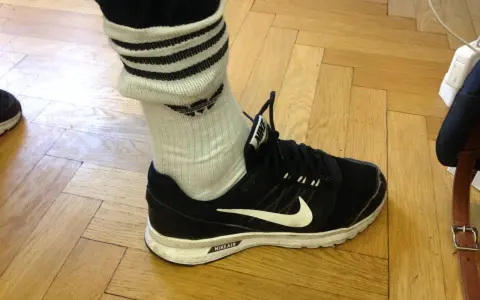 Schwarzer Nike-Schuh mit weißen Streifen an den Socken, die über den Knöchel reichen.
